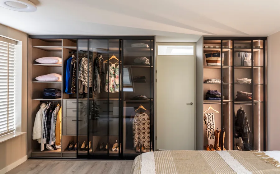 Slaapkamer met kledingkast op maat met verlichting en schuifdeuren met rookglas.