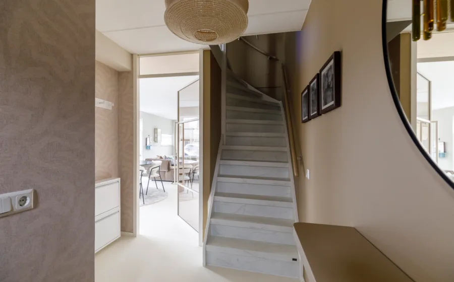 Hal met vloeiende lijnen, natuurgeïnspireerde behang en ovale spiegel.