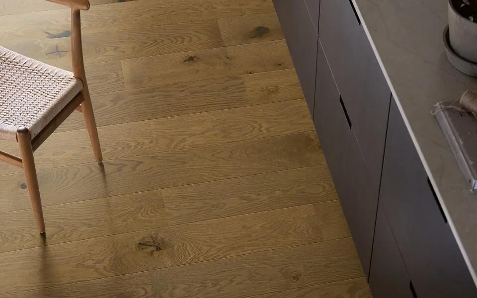 Donkere parket vloer van pergo naast zwart aanrechtblok