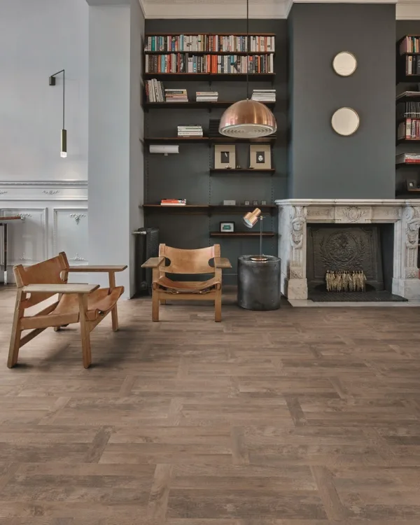 Woonkamer in landelijke stijl met vinylvloer, boekenkast, houtkachel en comfortabele stoelen.