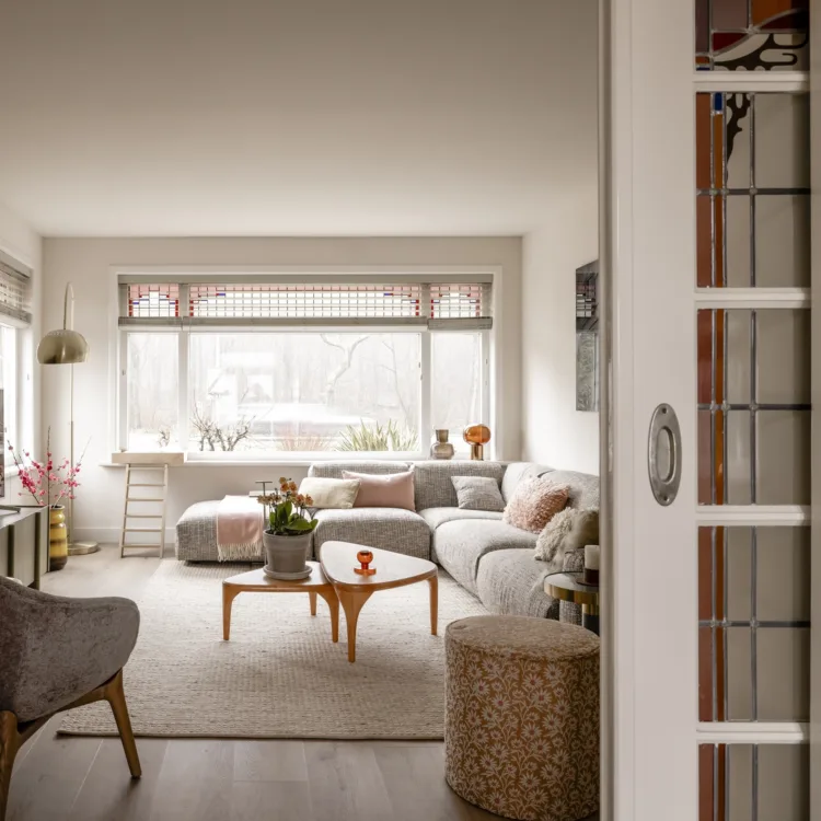 Woonkamer met houten vloer, geknoopt vloerkleed en kleurrijke glas-in-loodramen en ensuite deuren.