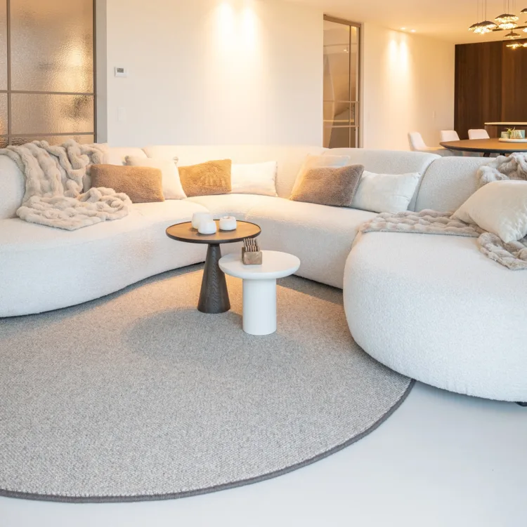 Woonkamer met loungebank, lichtgrijs organisch vloerkleed en sfeerverlichting